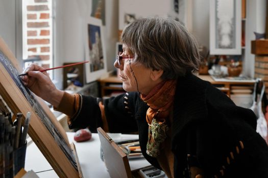 An elderly woman paints french gothic cathedral at home