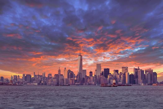 New York City Manhattan downtown skyline at dusk with skyscrapers illuminated over Hudson River panorama. Dramatic sunset sky