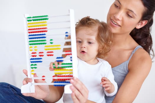 A mother and her baby daughter playing with an abacus.