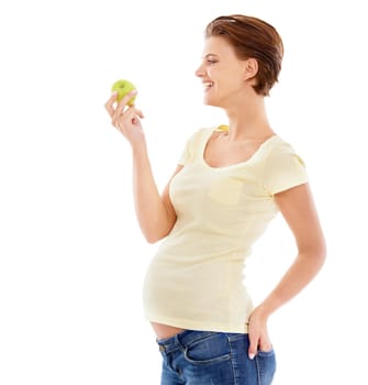 A pregnant woman looking at a crunchy green apple while isolated on a white background.