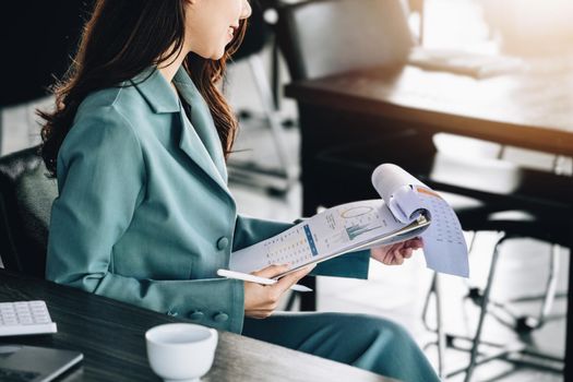 Young economists or accountants or financiers and investors are reviewing budget documents and using computers to study impact and risk assessments on corporate investment management