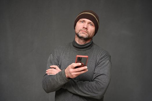 a man with a phone looks into the camera. Portrait on a gray background in the studio