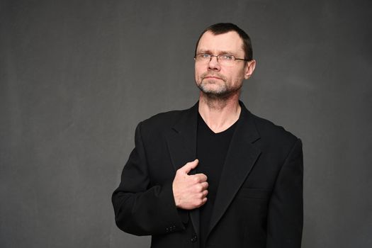 Businessman with glasses looks at the camera. Portrait on a gray background in the studio