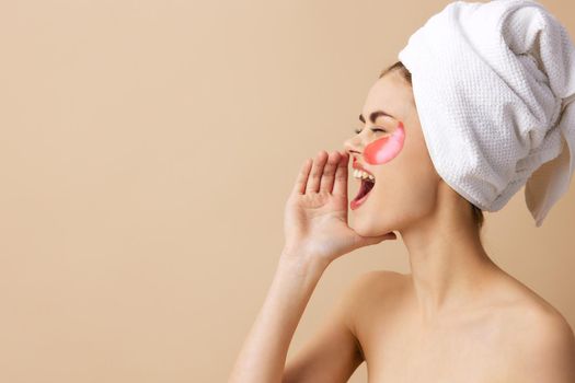 woman pink patches on the face with a towel on the head beige background. High quality photo