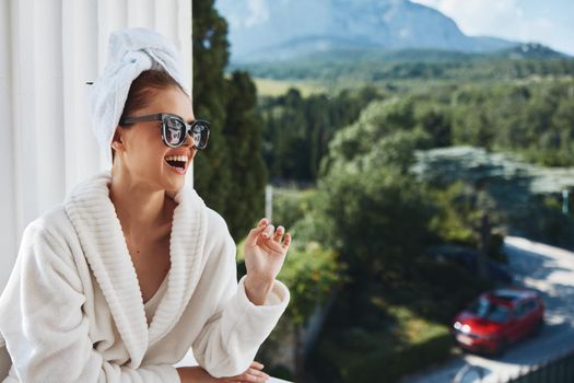 beautiful woman wearing sunglasses posing in a bathrobe on a balcony rest Relaxation concept. High quality photo