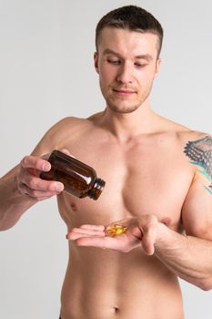 Fish oil is eaten by a man in the hands of vials and a glass bottle supplement, medicine treatment medical cure lifestyle, young closeup. translucent, background female giving dieting