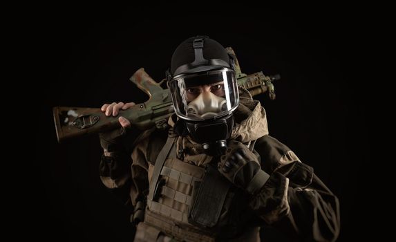 man in a military uniform and a gas mask holds a weapon with an angry expression of emotion