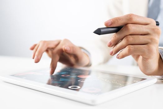 Man in business suit using tablet computer. Close-up of male hands holding pen and tablet gadget. Businessman at workplace in office. Mobile smart device in business occupation. Digital technology