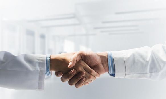 Close-up of the handshake between the two medics. Against the backdrop of the office