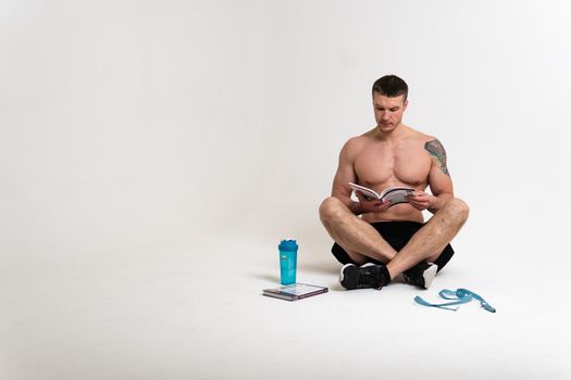 Bodybuilder reads the book on a white background isolated at the bottom of his head on his hands man handsome macho, muscle strong reader guy adult, sexy standing. Health winner biceps, vision tan