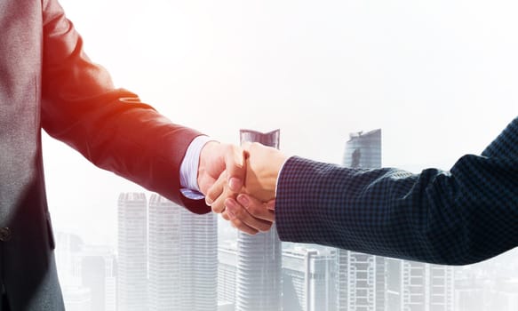 Close-up of the handshake of businessmen. Against the backdrop of the cityscape