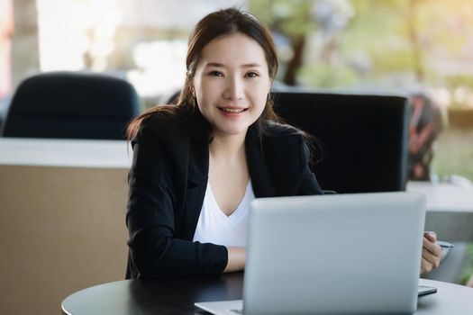 A female worker smiling happily while using a computer in the office