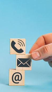 Website page contact us or e-mail marketing concept. Hand putting wooden block cube symbol telephone, email, address.