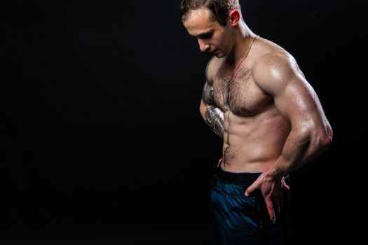 Man on black background keeps dumbbells pumped up in fitness muscle chest sport, man athletic dumbbell, pectoral. handsome adult, gym fit hands behind your back, press tense beautiful body