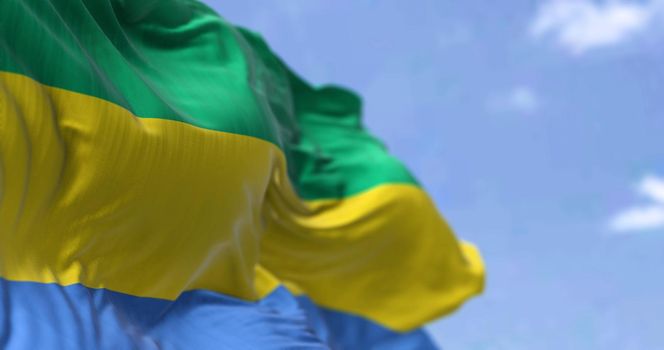 Detail of the national flag of Gabon waving in the wind on a clear day. Gabon is a country on the west coast of Central Africa. Selective focus.