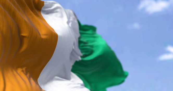 Detail of the national flag of Ivory Coast waving in the wind on a clear day. Ivory Coast is a country on the southern coast of West Africa. Selective focus.