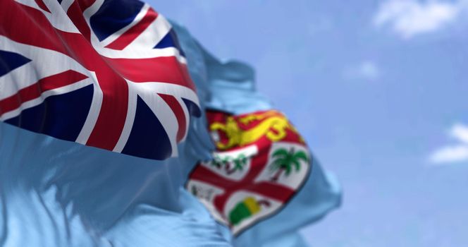 Detail of the national flag of FIji waving in the wind on a clear day. Fiji is an island country in Melanesia, part of Oceania in the South Pacific Ocean. Selective focus. Seamless slow motion