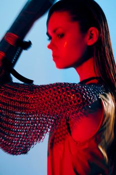 photo pretty woman red light silver armor chain mail fashion blue background. High quality photo