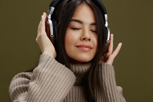 pretty woman in a sweater listening to music with headphones fun studio model. High quality photo