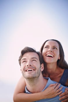 A handsome man piggybacking his loving wife outdoors.