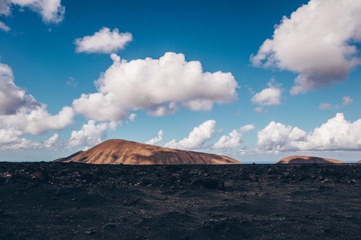 Amazing panoramic landscape of volcano craters in Timanfaya national park. Popular touristic attraction in Lanzarote island, Canary islans, Spain. Artistic picture. Beauty world. Travel concept