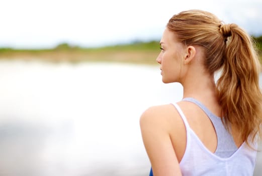 Rearview shot of a young woman sitting outdoors.