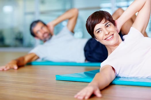 Happy woman and man exercising on yoga mat at gym.