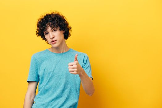 man with curly hair thumb up smile yellow background. High quality photo