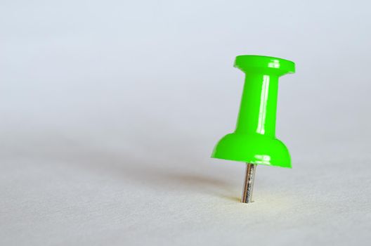 Green push pin. Closeup photography of green thumbtack.