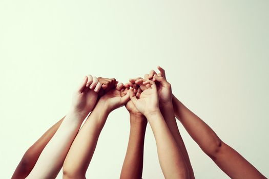 Cropped shot of a group of people holding each others thumbs with their hands raised.