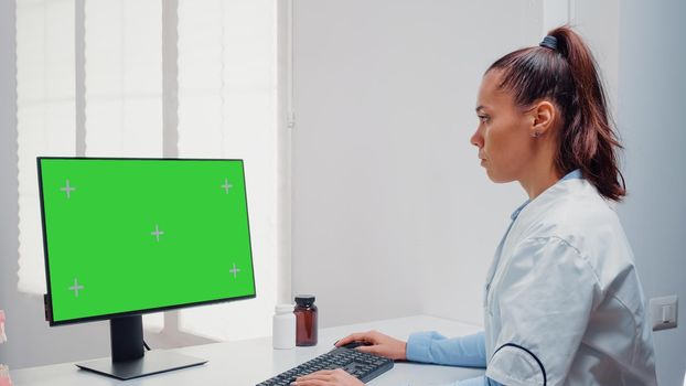 Dentist working with horizontal green screen on computer for teethcare at dental office. Woman using keyboard and monitor with chroma key for mockup template and isolated background