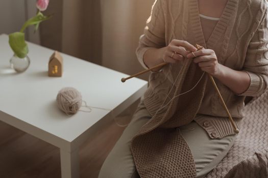 Women's hands knitting from woolen beige yarn