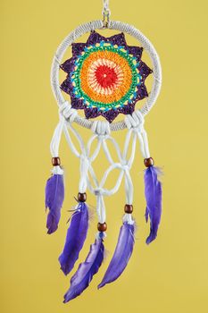 Handmade amulet dream catcher on a yellow background, protecting the sleeper from evil spirits and diseases