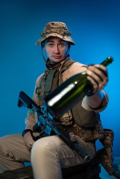 drunk army soldier in military clothes with a bottle of alcohol in his hand offers to drink