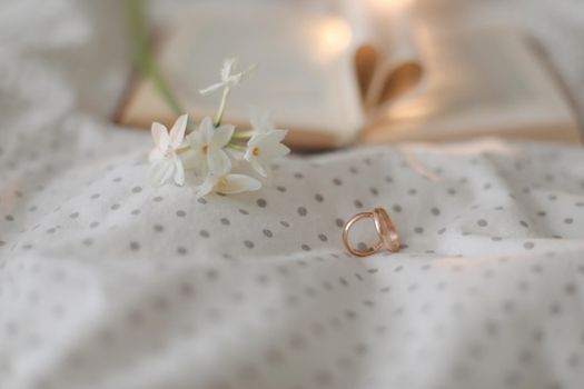 Golden ring and open book with folded sheets in heart shape in bed. Wedding concept, Happy Valentine's Day.