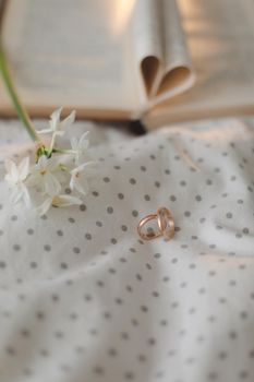 Golden ring and open book with folded sheets in heart shape in bed. Wedding concept, Happy Valentine's Day.