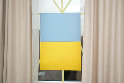 Flag of Ukraine on the window sealed with tape. No war. War in Ukraine