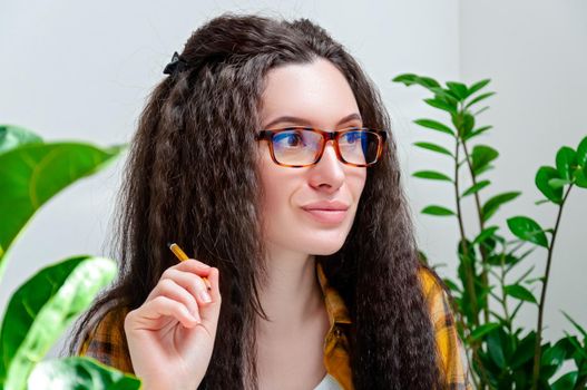 Close-up portrait beautiful thoughtful woman in glasses looks away on workplace. Woman working at home.