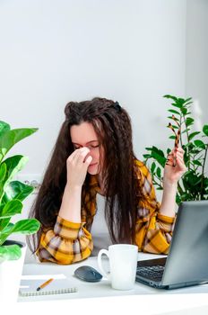 Beautiful woman rubs her eyes due to fatigue from working at a laptop. Woman working at home, undergoing training, watching webinar, online shopping.