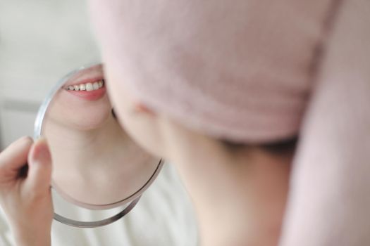 young smiling woman with a towel on head looking in the mirror