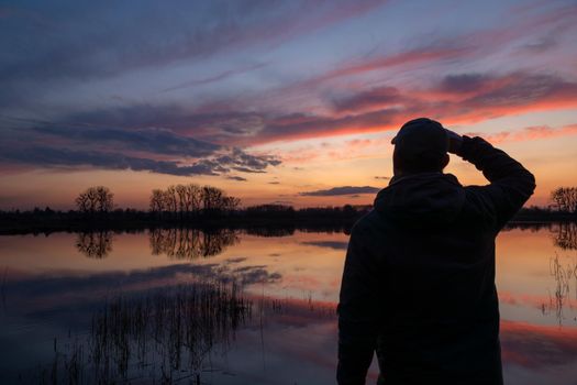 A man standing on the shore of a lake after sunset, Stankow, Poland