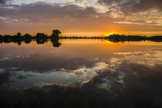 Sunset and clouds over a calm lake, summer view