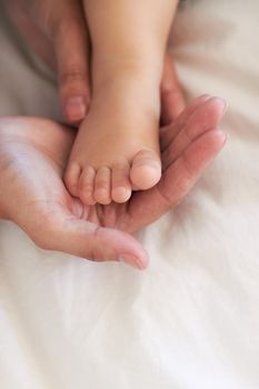 Cropped image of a mothers hands holding her baby boys foot.