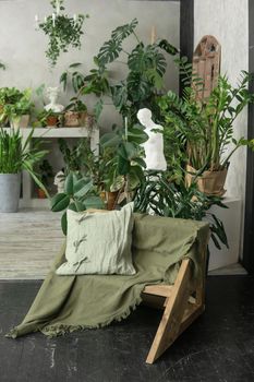 A fragment of the interior with a variety of indoor plants and plaster sculptures. Urban jungle concept. Biophilia design.