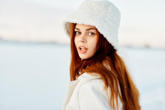 pretty woman in a white coat in a hat winter landscape walk nature. High quality photo