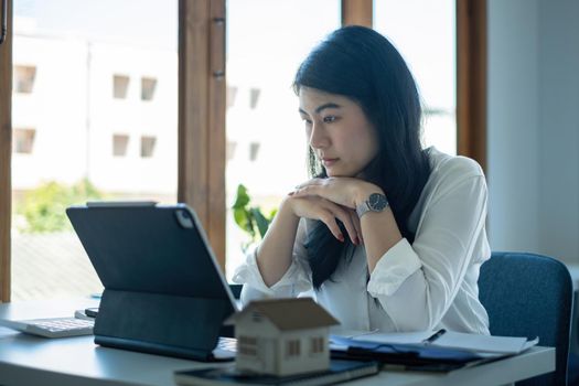 A stressed woman holding and checking house model .Real Estate House Appraisal And Inspection and Insurance concept