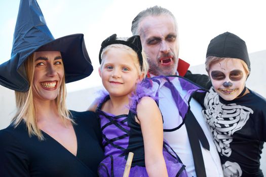A fun family dressed up for Halloween, posing together.