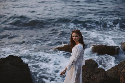 pretty woman with wet hair in white dress cliff. High quality photo