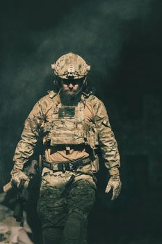 A bearded soldier in a special forces uniform walks through an abandoned building after a successful mission. Selection focus. High-quality photo