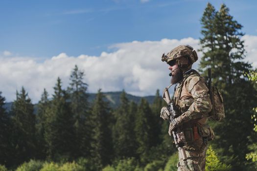 War concept. A bearded soldier in a special forces uniform fighting an enemy in a forest area. Selective focus. High-quality photo